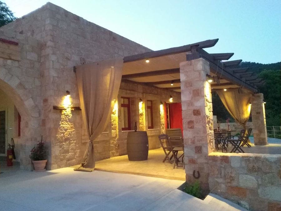 illuminated 'Piperis Winery' terrace with stone columns by night